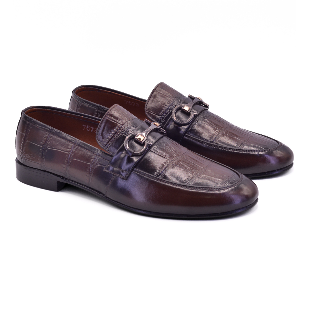 Pair of brown leather loafers with a copper buckle on a white background